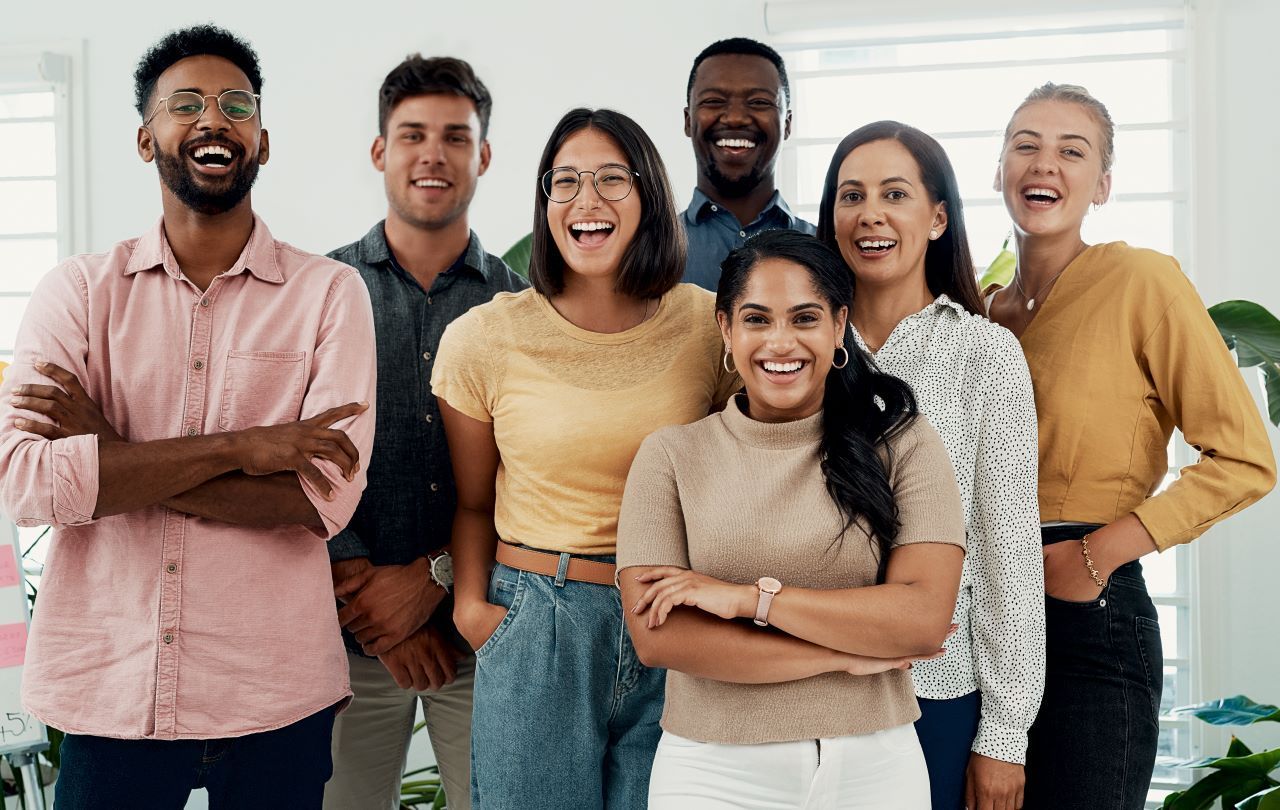 Group of diverse people smiling, posing in an office setting.