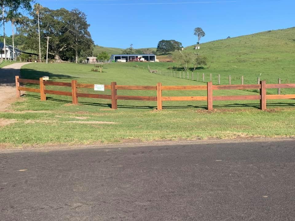 Wooden Fence Surrounds A Grassy Field With A House In The Background — Lawrence Williams Fencing in Goolmangar, NSW