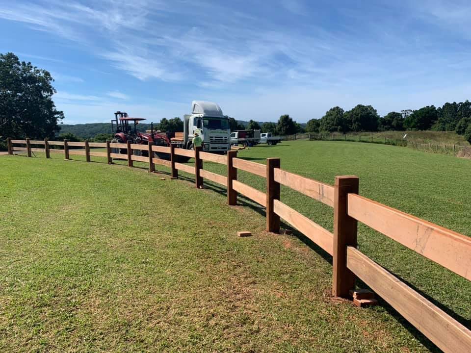 A Wooden Fence Surrounds A Grassy Field With A Truck In The Background — Lawrence Williams Fencing in Goolmangar, NSW