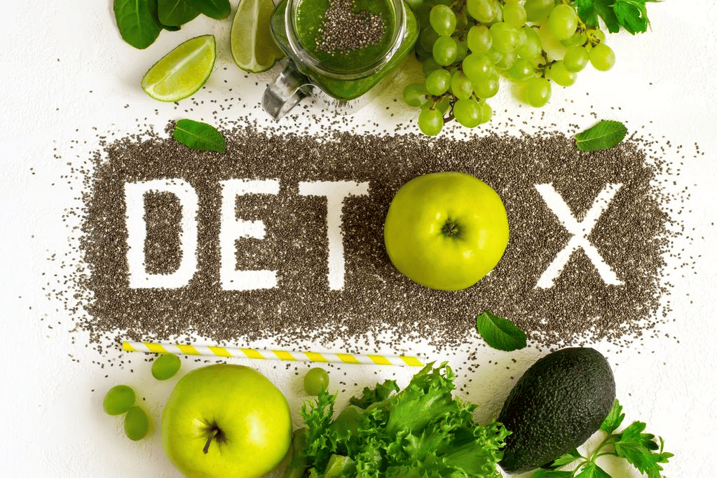 The word detox is written in chia seeds surrounded by fruits and vegetables.