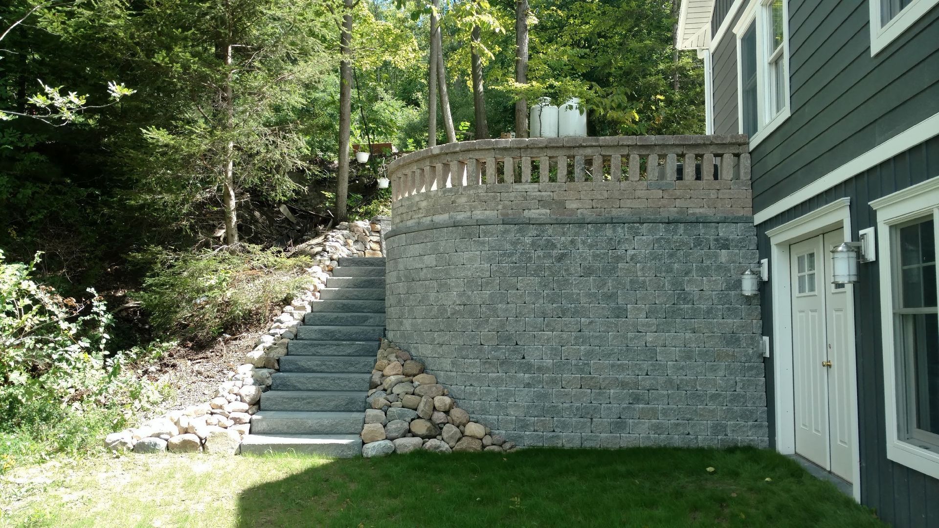 A house with a stone wall and stairs leading up to it