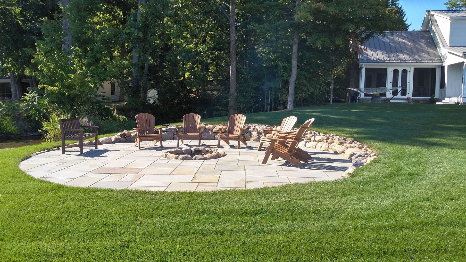 A patio with chairs and a fire pit in the middle of it