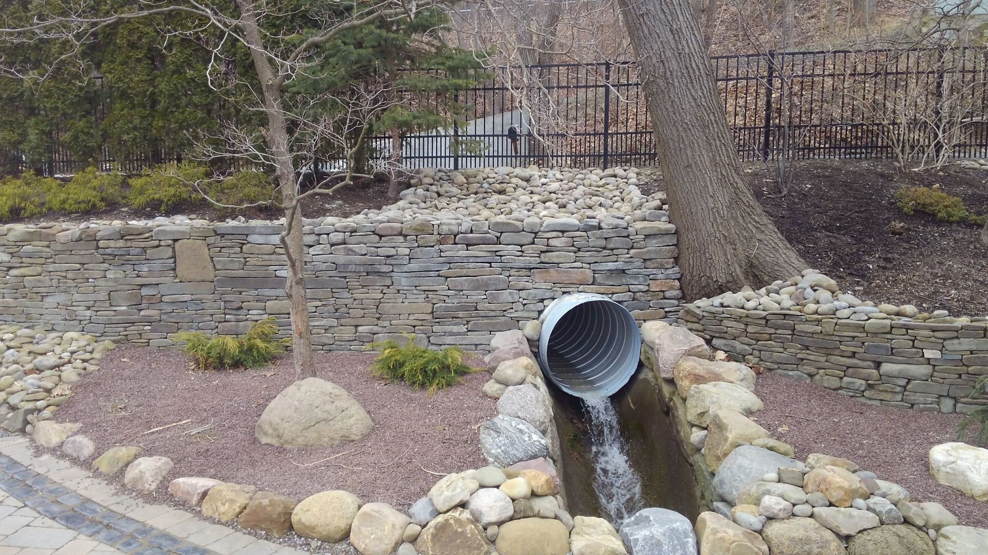 A pipe is draining water into a stream surrounded by rocks