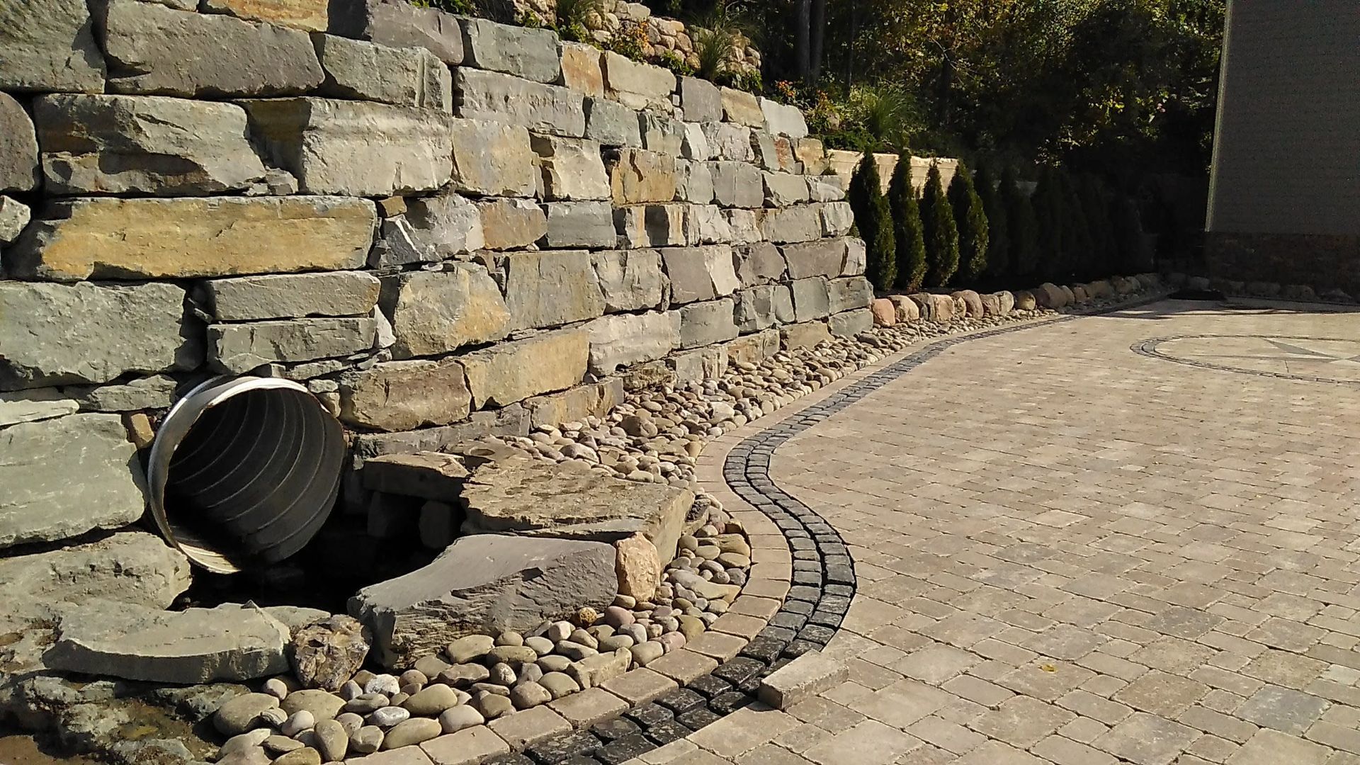 A pipe is coming out of a hole in a stone wall