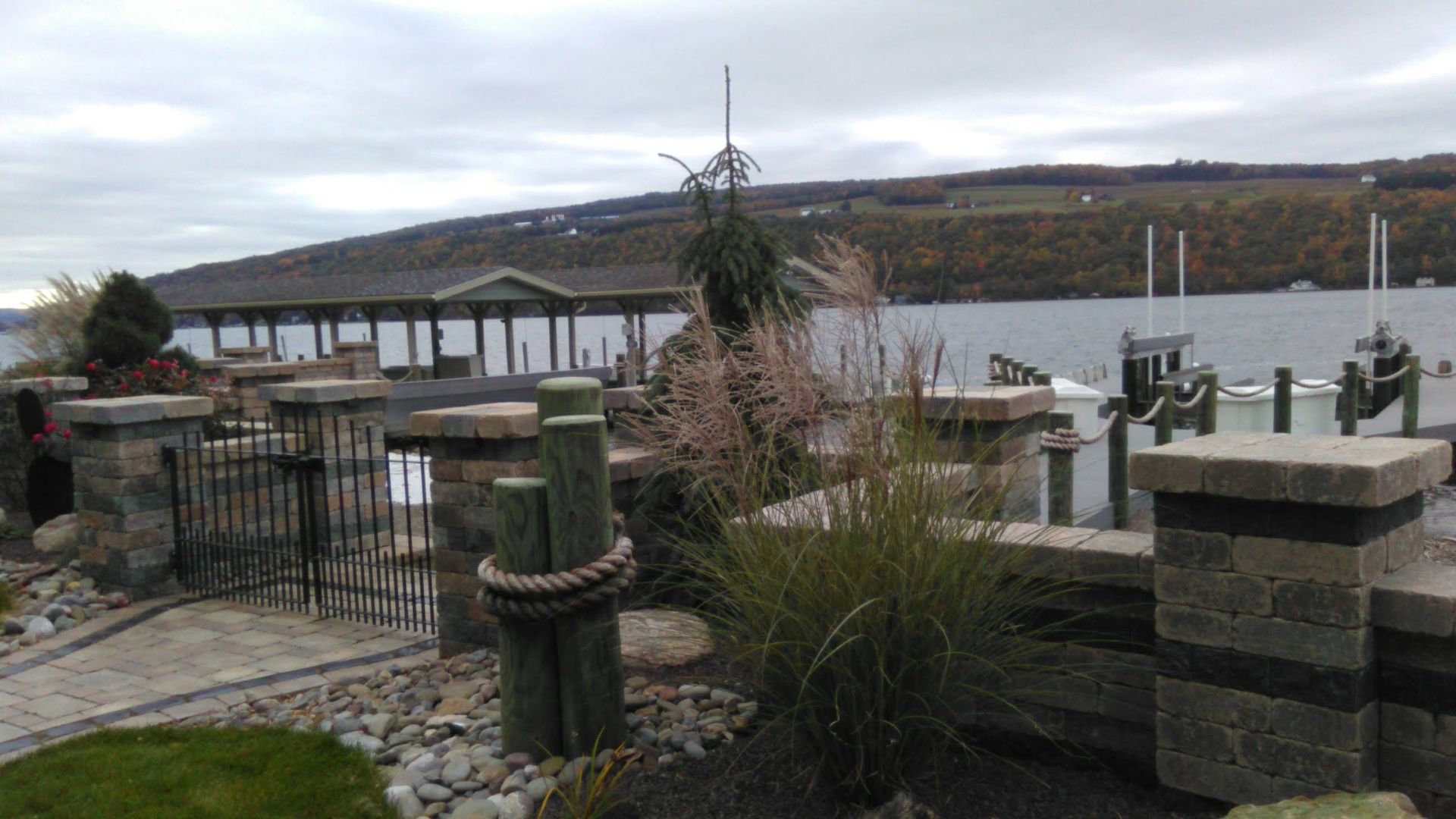 A dock with boats docked in the water and a house in the background