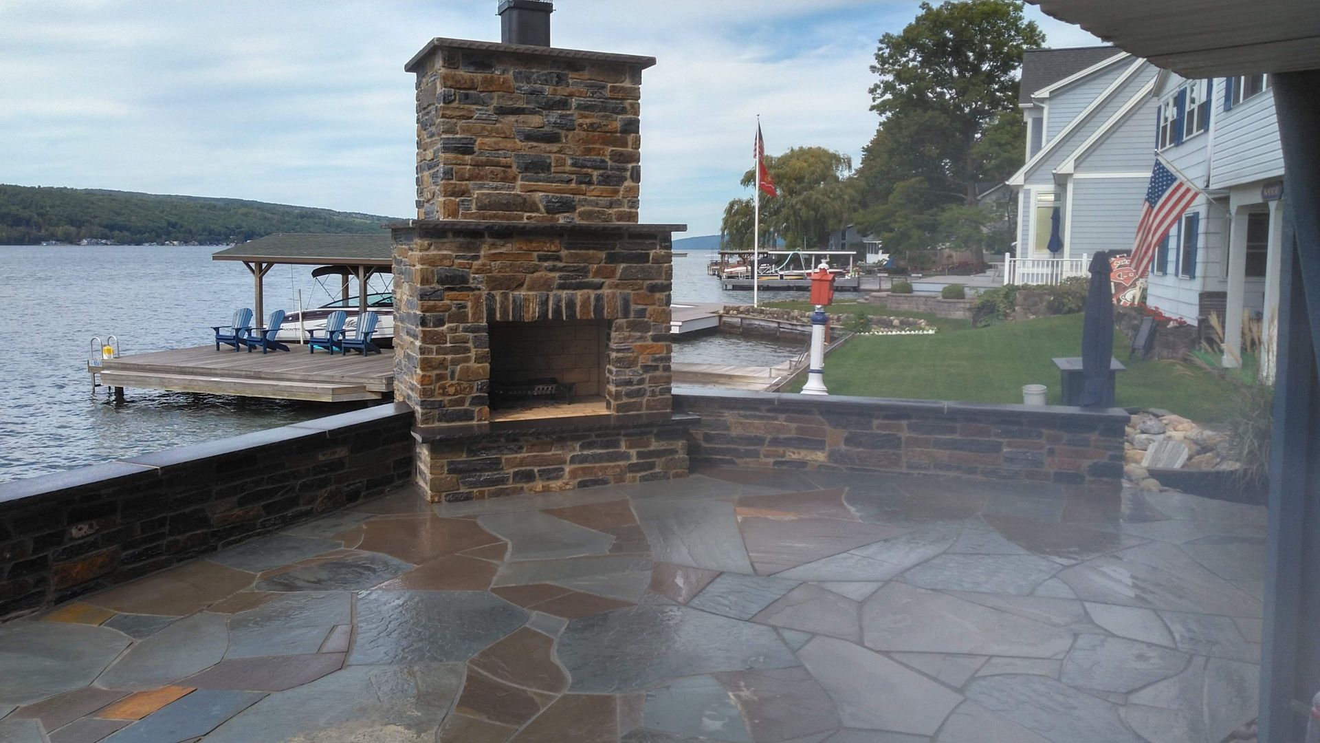 A stone fireplace is sitting on a patio next to a lake