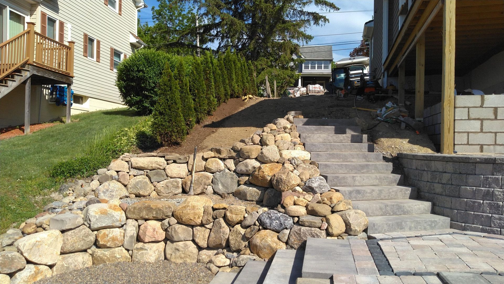 A stone wall and stairs are being built in front of a house