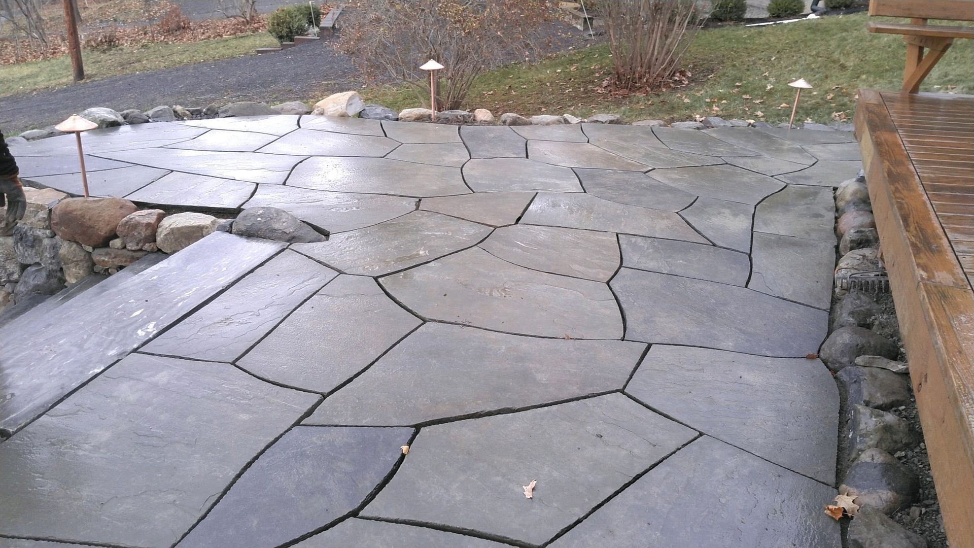 A stone patio with a wooden deck in the background