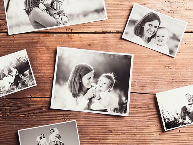 A bunch of black and white photos of a family on a wooden table.