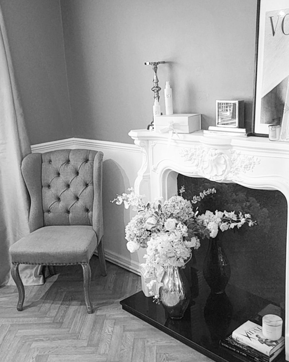 A black and white photo of a living room with a fireplace and a chair.