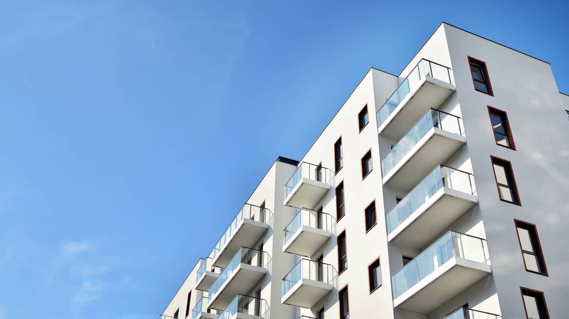A white apartment building with balconies against a blue sky