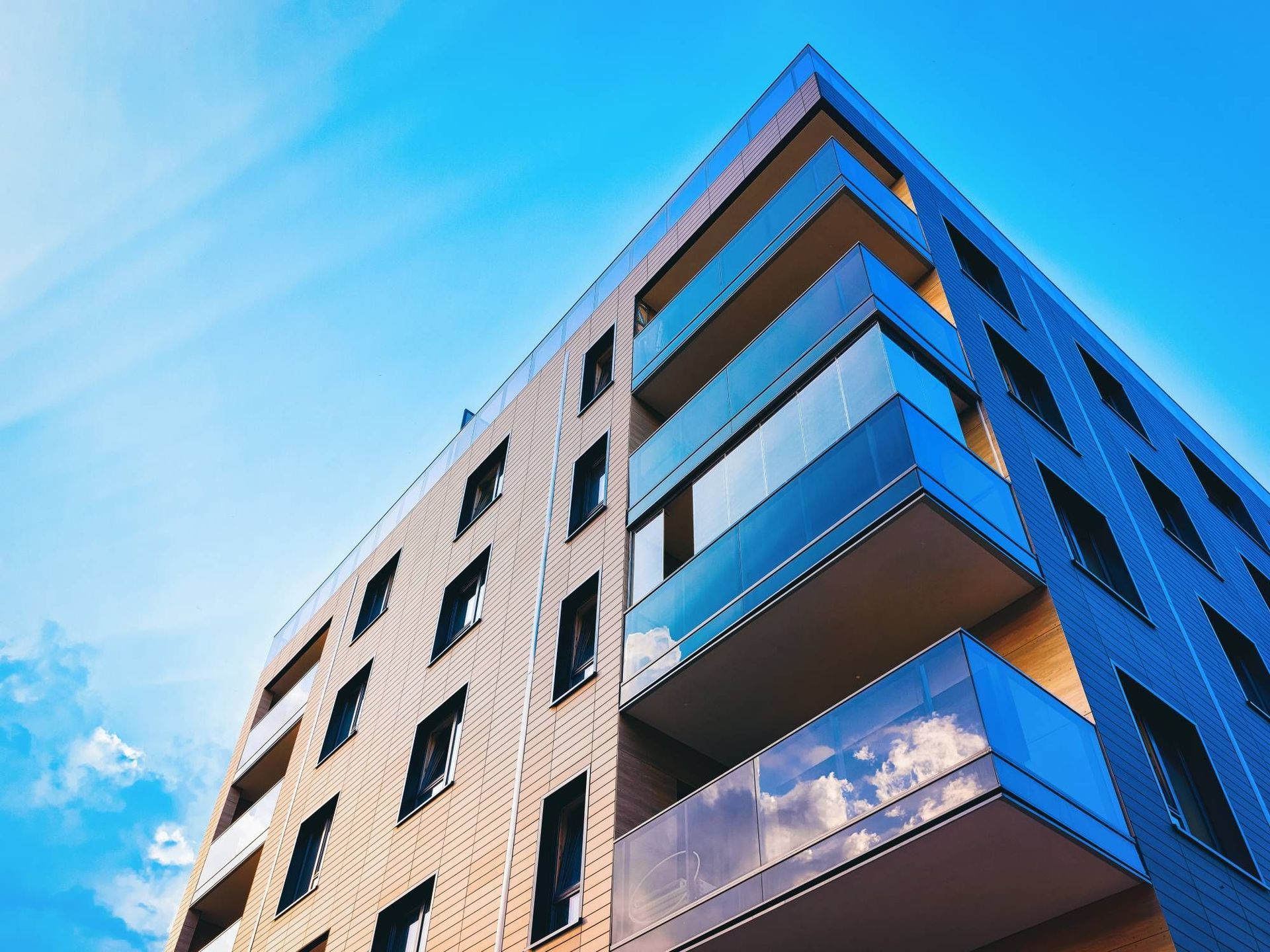 Looking up at a tall building with balconies against a blue sky