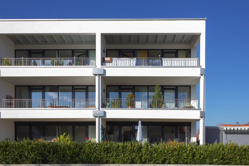 A large white apartment building with lots of windows and balconies.
