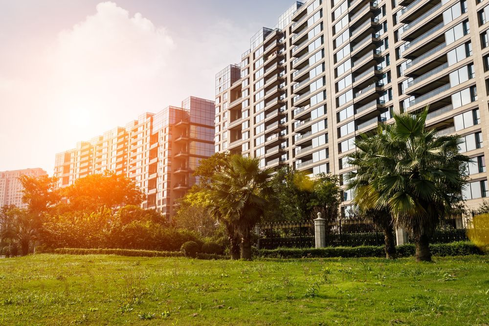 A large building with a lot of windows is surrounded by trees and grass.