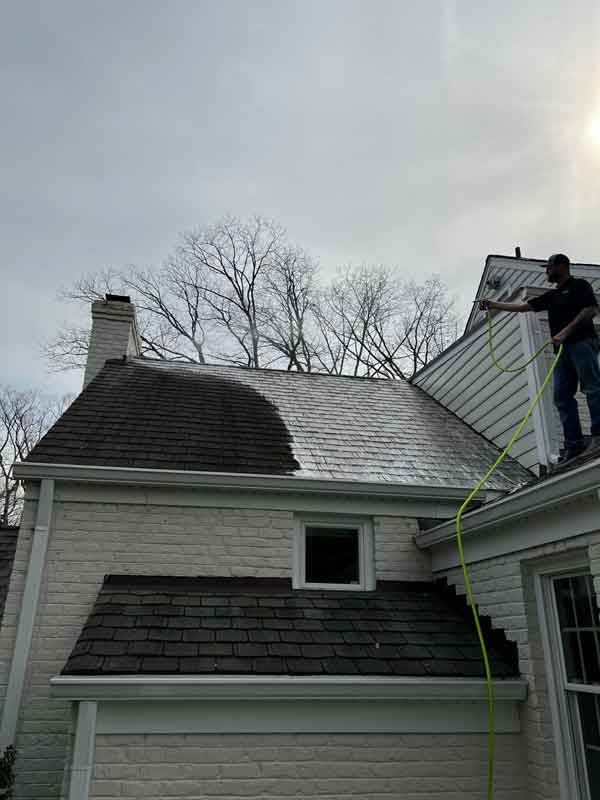 Man working on a roof cleaning project in Richmond, VA