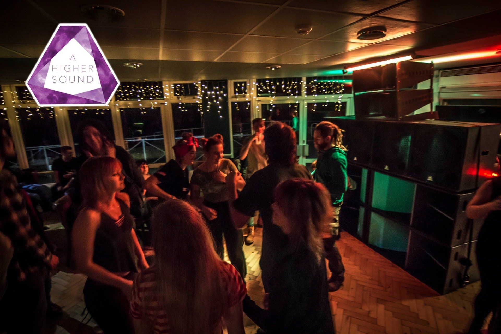 People dancing in a dimly lit venue with a logo for