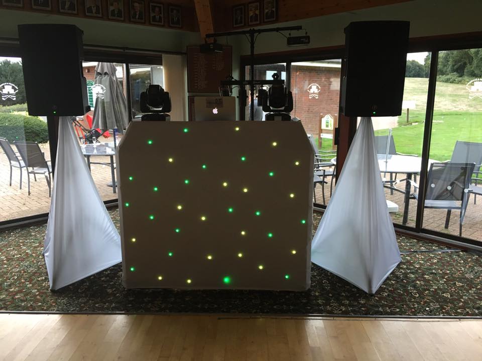 DJ setup: speakers, lights, and booth on a rug, with a patio backdrop.