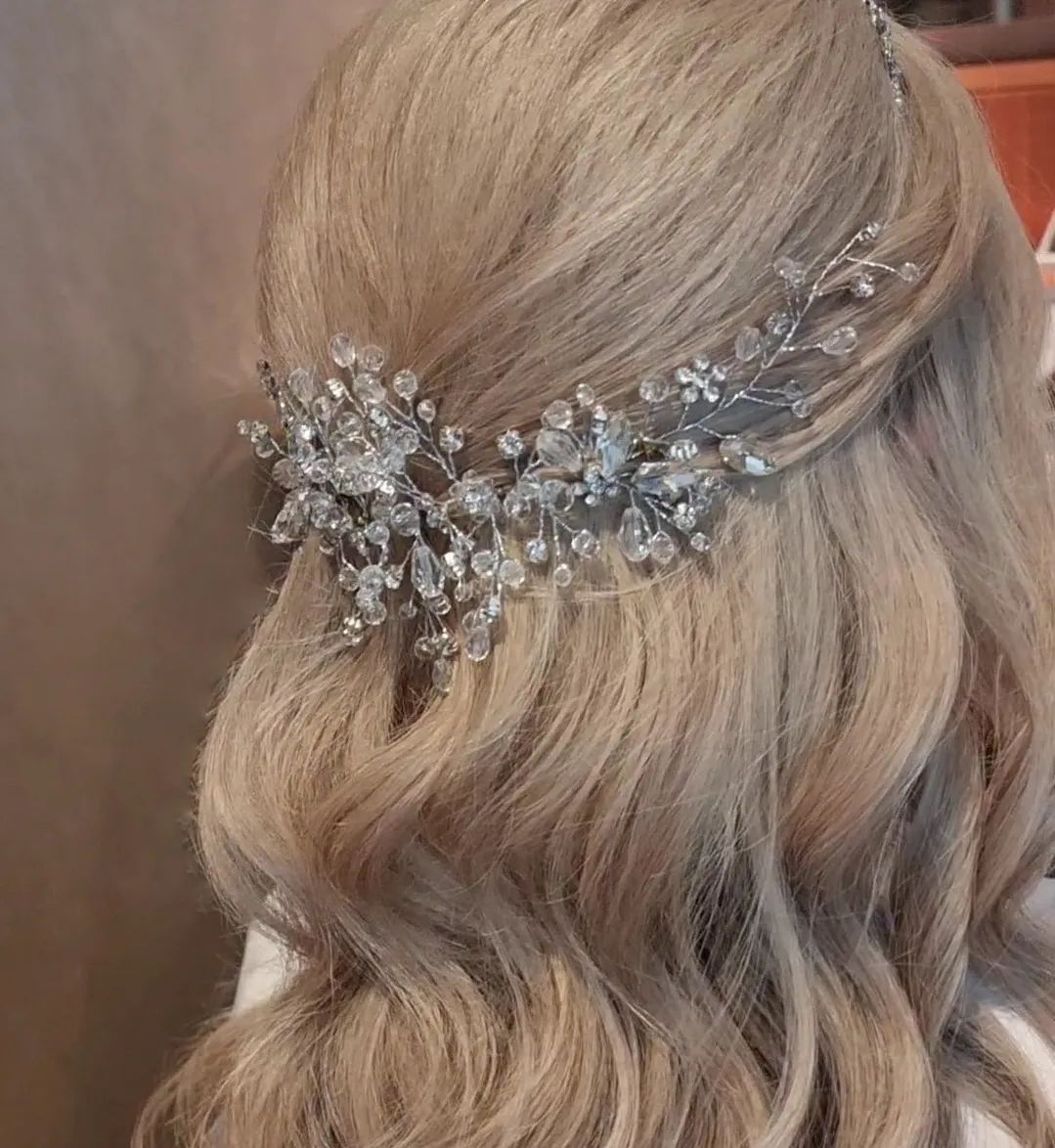Blonde hair styled in waves with a silver crystal hair accessory.