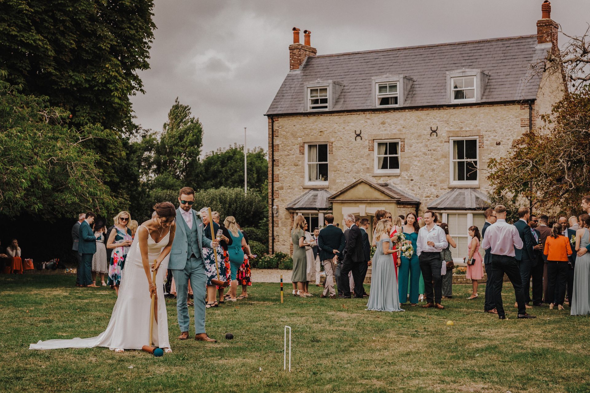 Wedding guests playing croquet on a lawn with a historic building in the background.