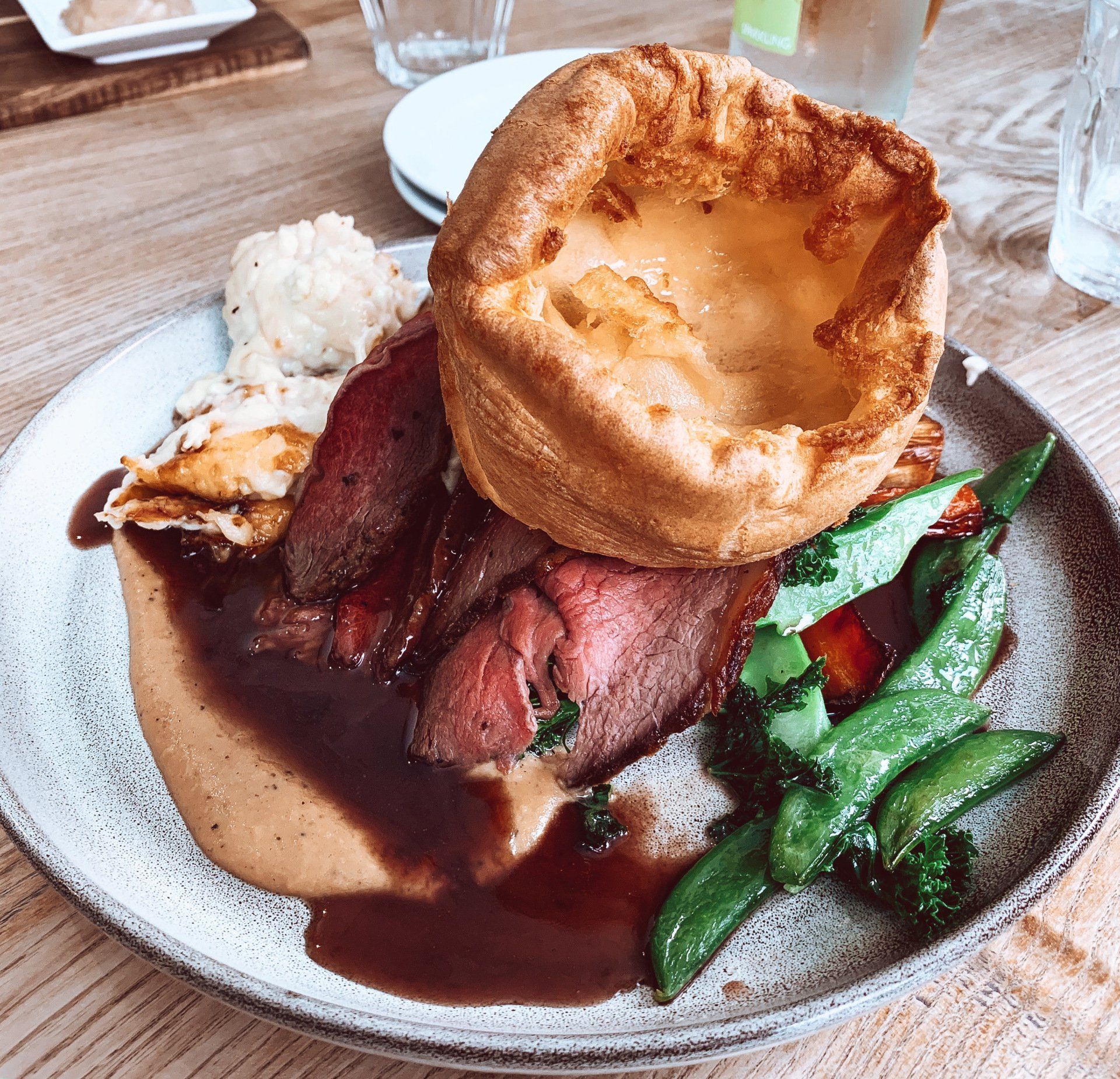 Roast beef dinner with Yorkshire pudding, gravy, vegetables, and mashed potatoes on a plate.