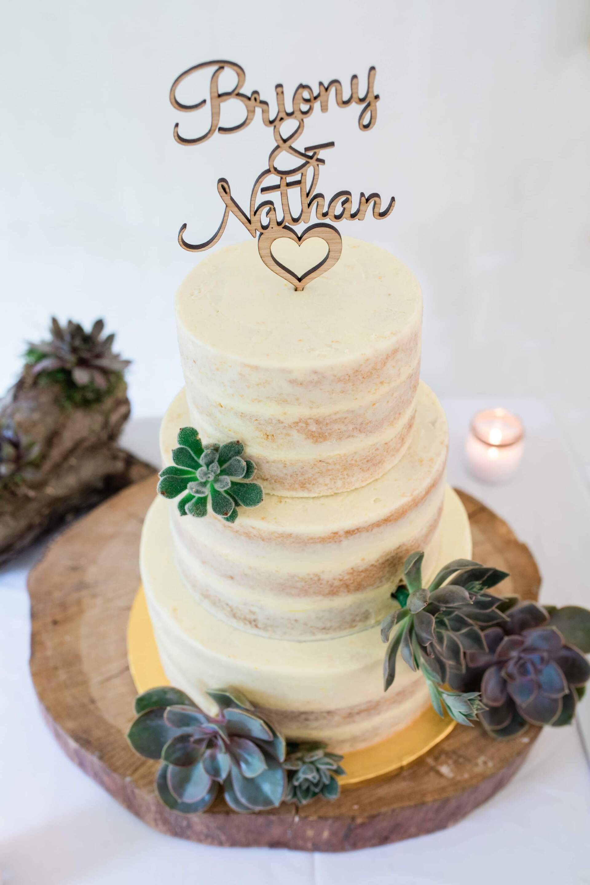 Three-tiered naked wedding cake with succulent and wooden topper that says