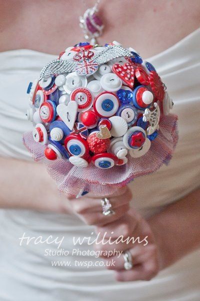 Bride holding a button bouquet, red, white, and blue, with a pink lace handle.