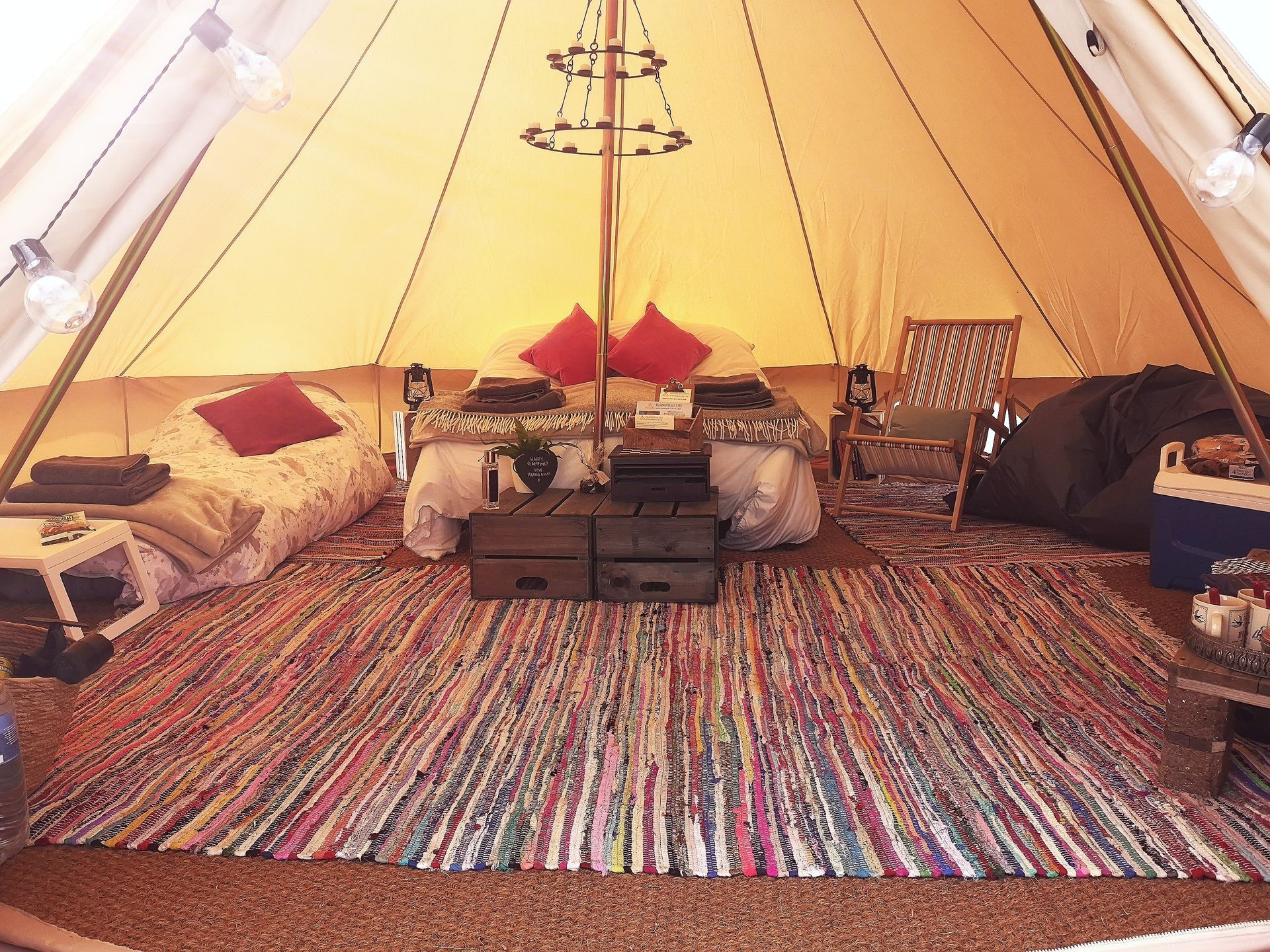 Inside of a glamping tent with bed, rugs, and string lights.