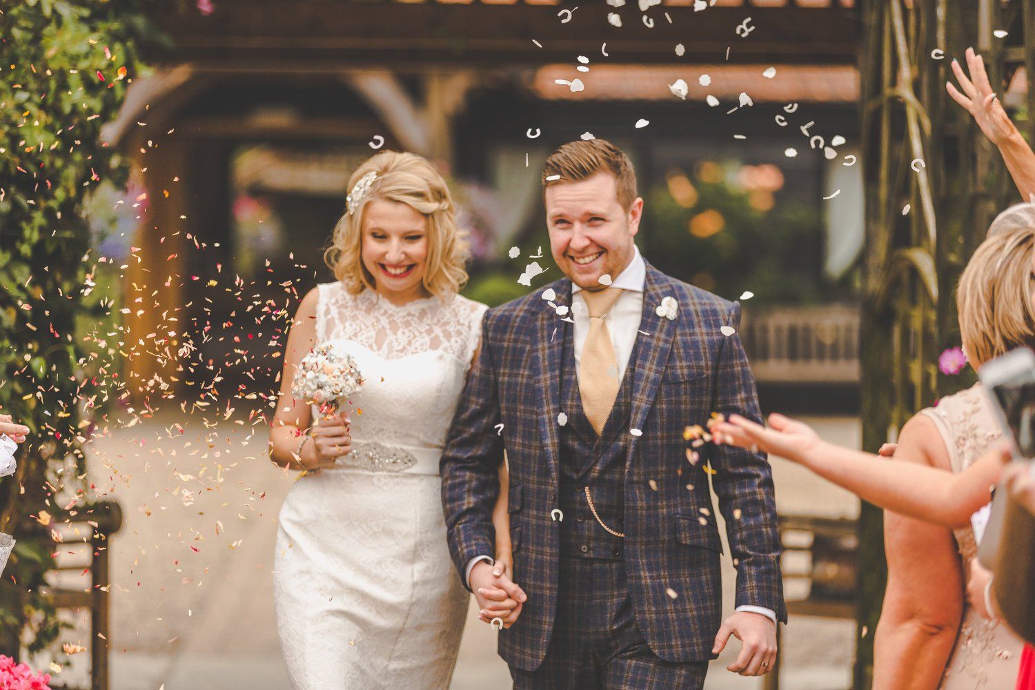 Newlyweds walk, smiling, through confetti after their ceremony.