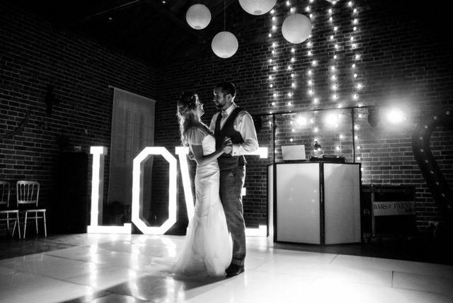 Bride and groom dance on a lit floor;