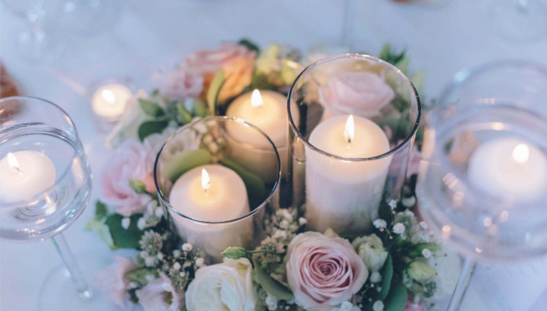 Candles and flowers on a table create a romantic centerpiece, illuminated with soft light.
