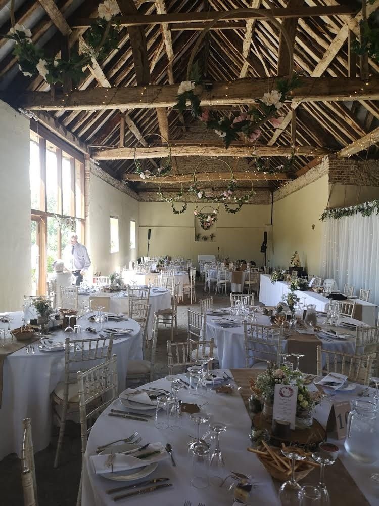 Wedding reception hall set up with white tablecloths, chairs, and floral decorations.