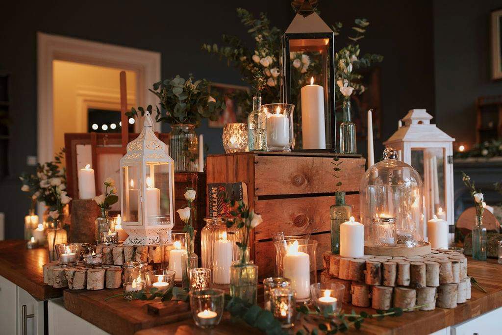 Wedding reception table with candles, lanterns, flowers, and wooden elements.