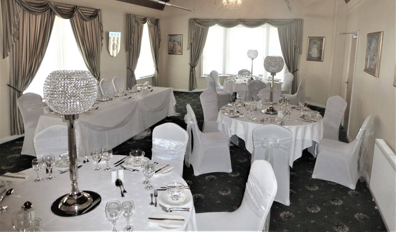 Elegant banquet hall, white table settings, round and rectangular tables, draped with white linens, crystal centerpieces.