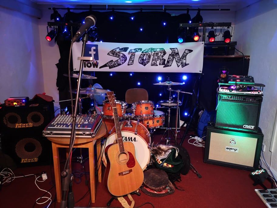 A band's stage setup: drums, guitar, amplifier, mixer, and a banner reading