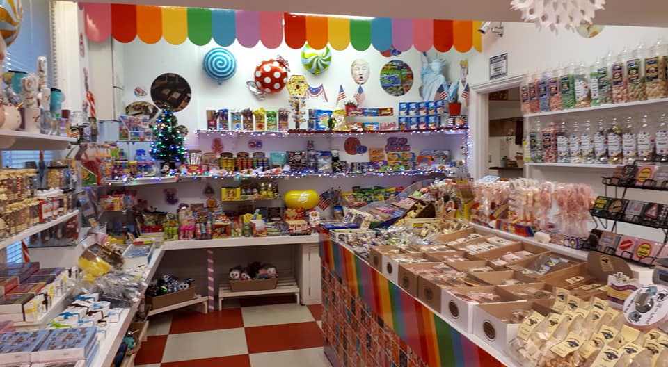 Candy store interior with colorful shelves, treats, and a rainbow-themed design.