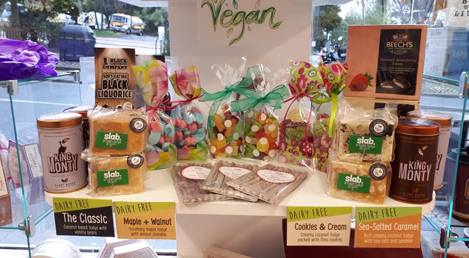 Vegan sweets display in a shop window, featuring baked goods, candies, and packaged treats.