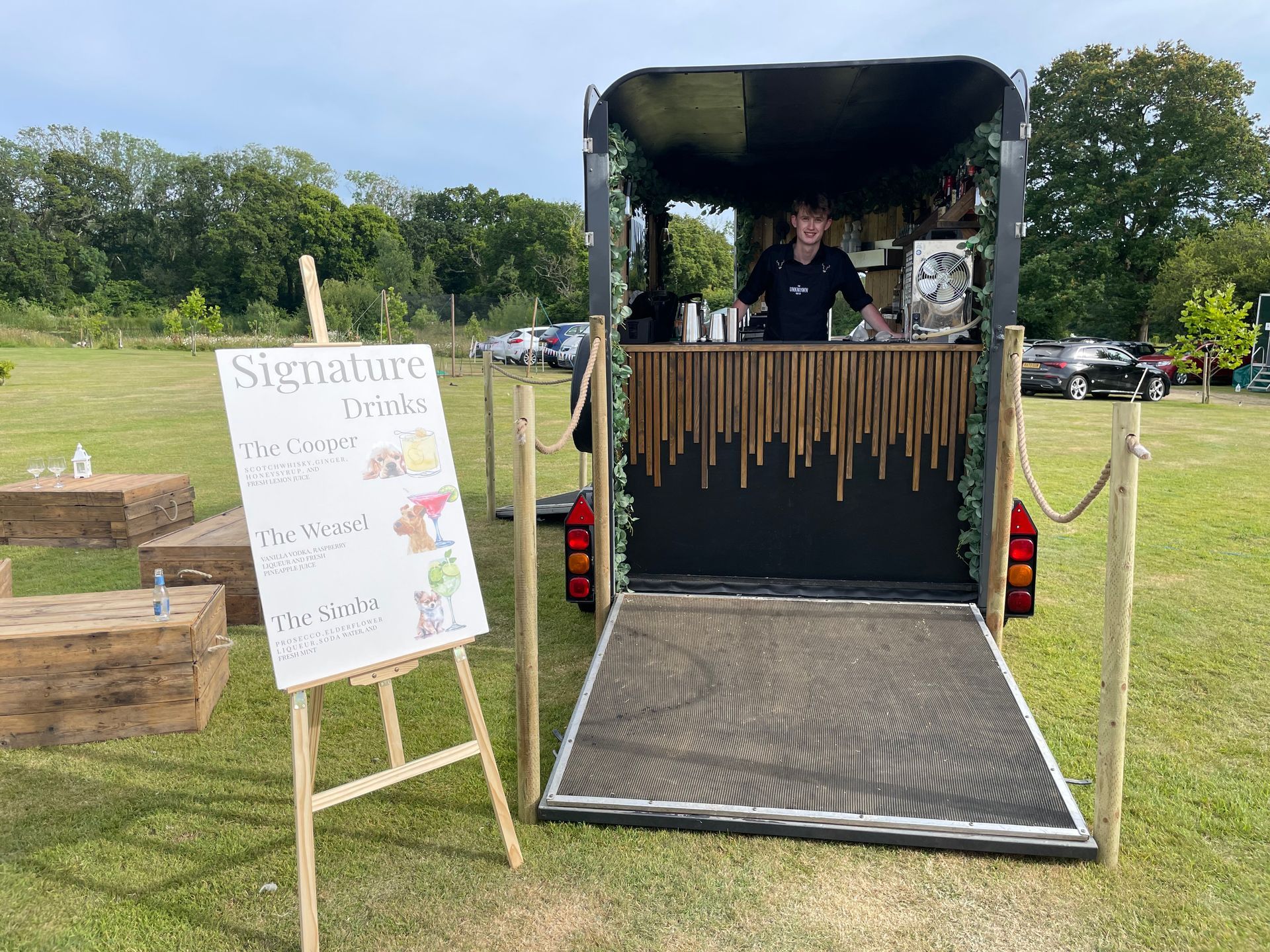 Mobile bar in a trailer with a bartender, serving signature drinks, outdoors.