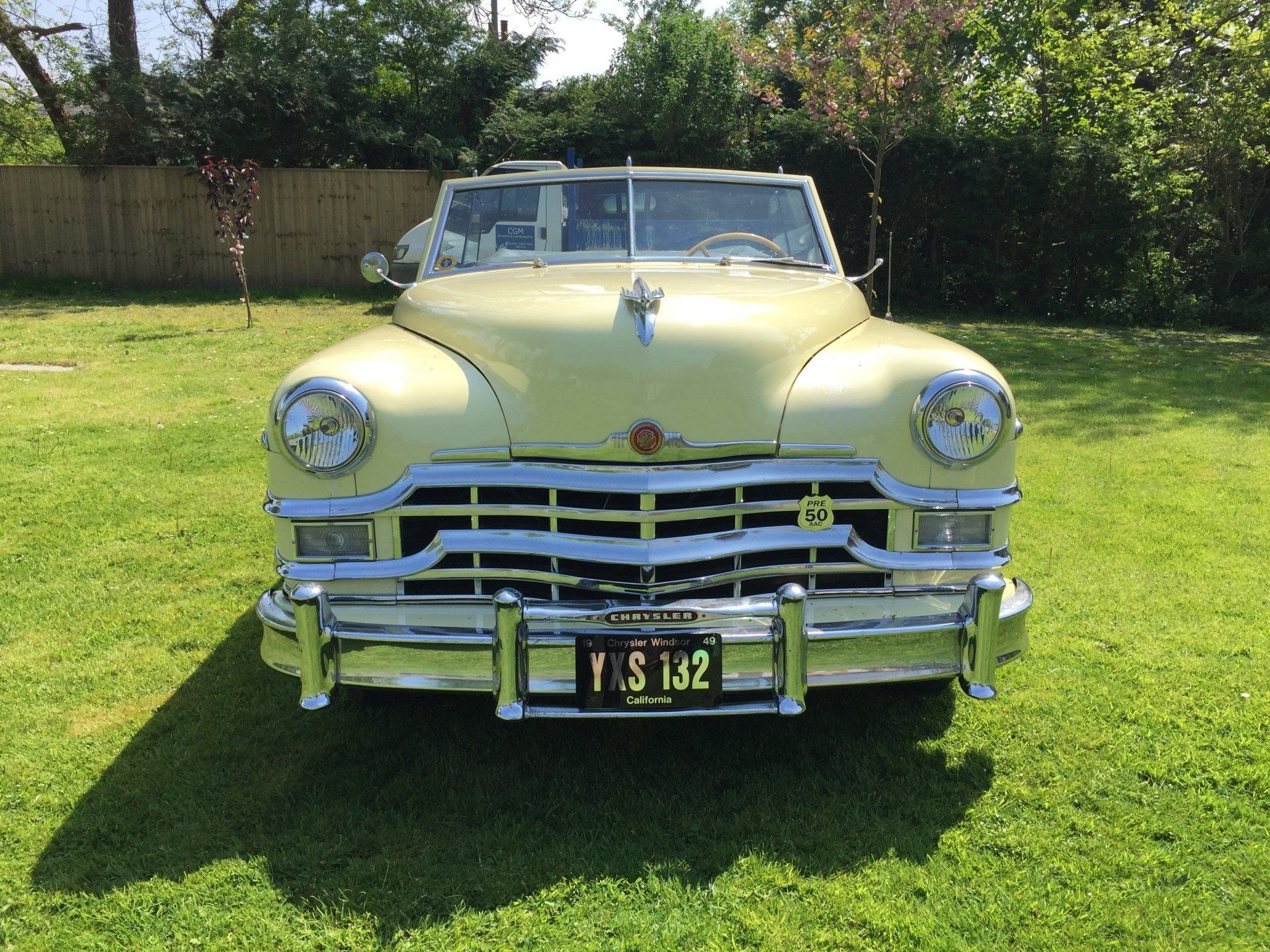 Yellow vintage convertible car parked on grass.