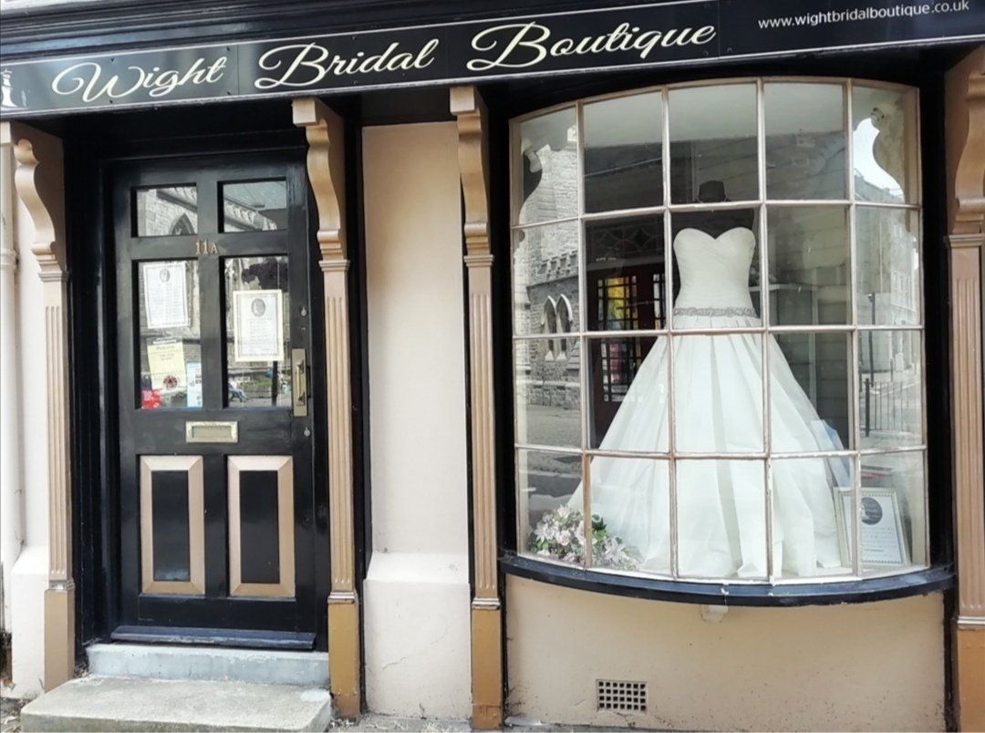 A bridal boutique storefront with a wedding dress in the window and a black door.