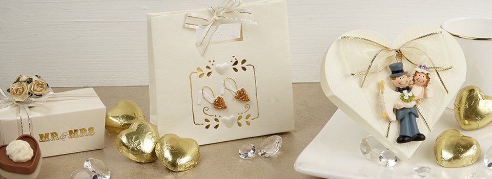 Wedding favors with heart-shaped chocolates, a gift bag, and a heart-shaped figurine of a bride and groom.