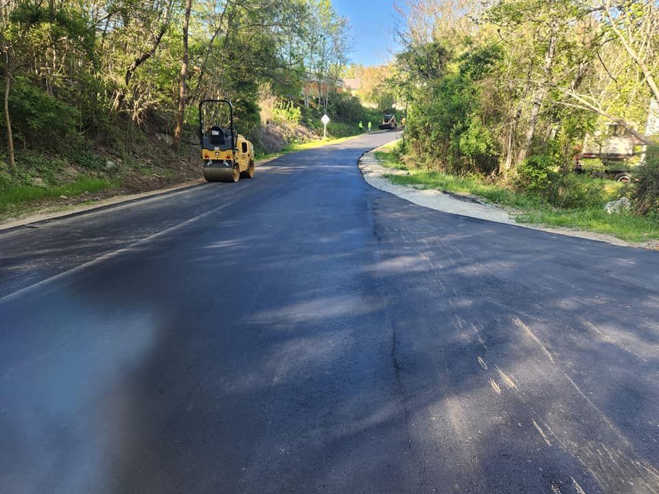A yellow roller is rolling asphalt on a curvy road