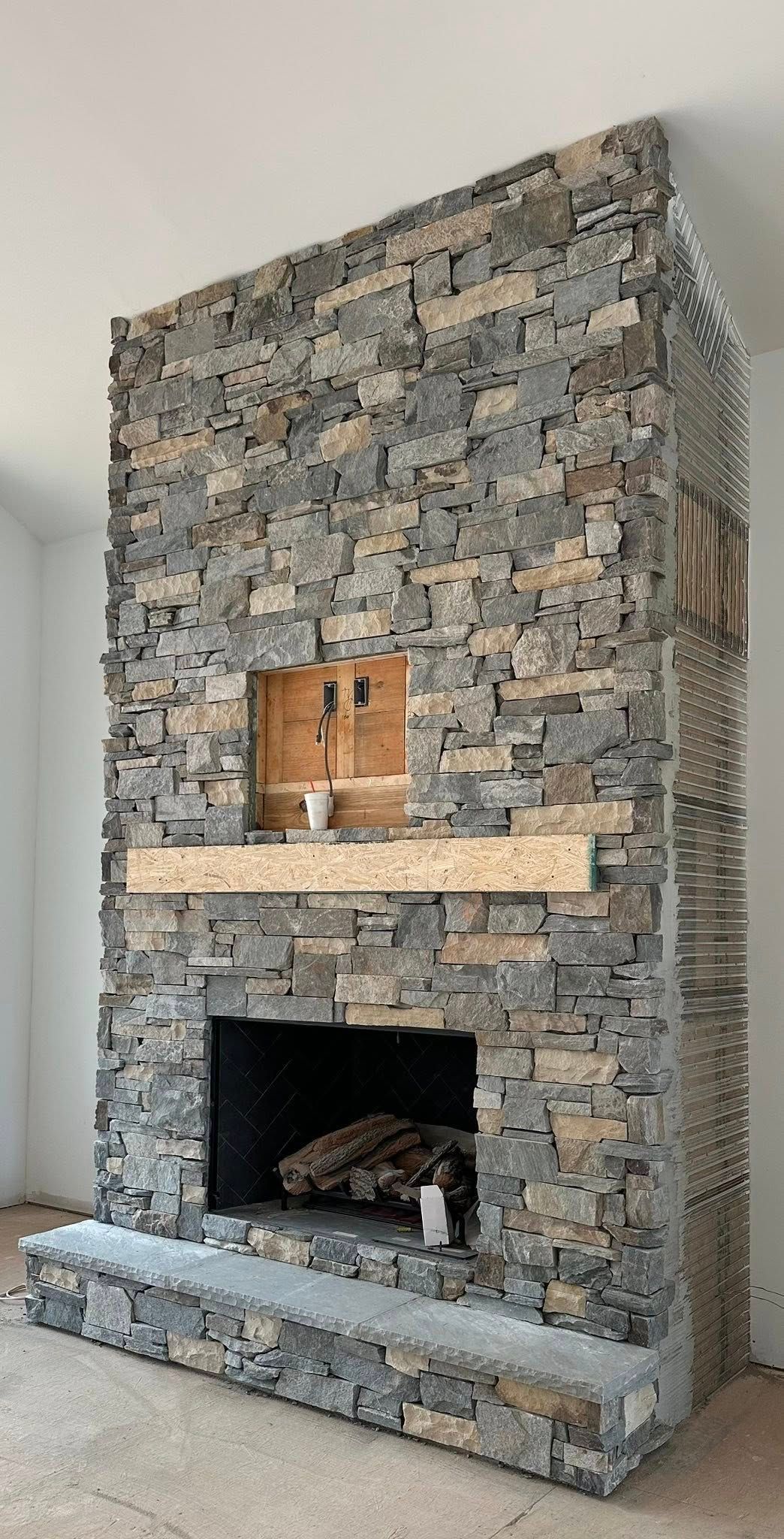 Stone-faced indoor fireplace with a mantel and a small decorative barrel on top