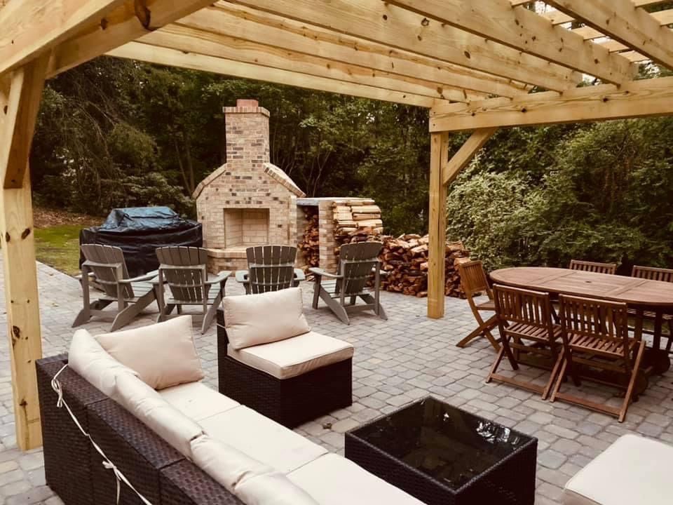 Covered patio with wicker seating, dining table, fire pit, and outdoor brick fireplace
