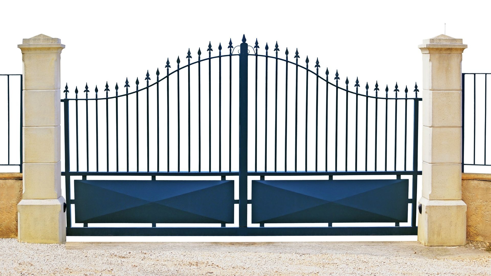 Dark blue wrought-iron gate with decorative top, between stone pillars, set in a gravel area.
