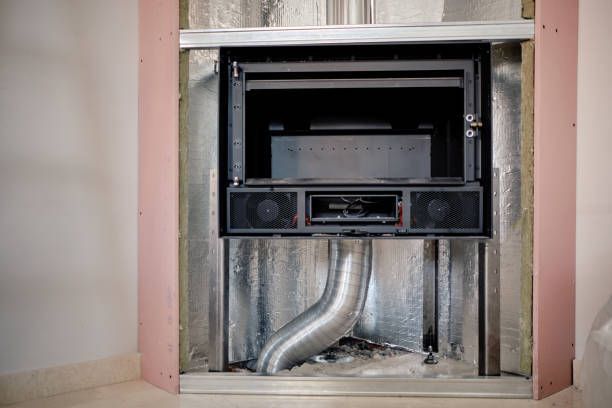 Fireplace insert installed in a wall opening, with exposed ductwork, insulation, and framing.