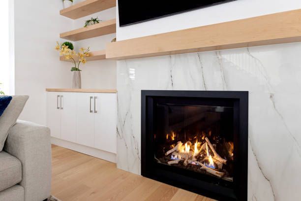 Modern fireplace with marble surround, black trim, and a burning fire.
