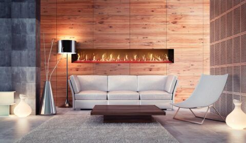 Modern living room with white sofa, chair, fireplace, wooden wall, lamp.