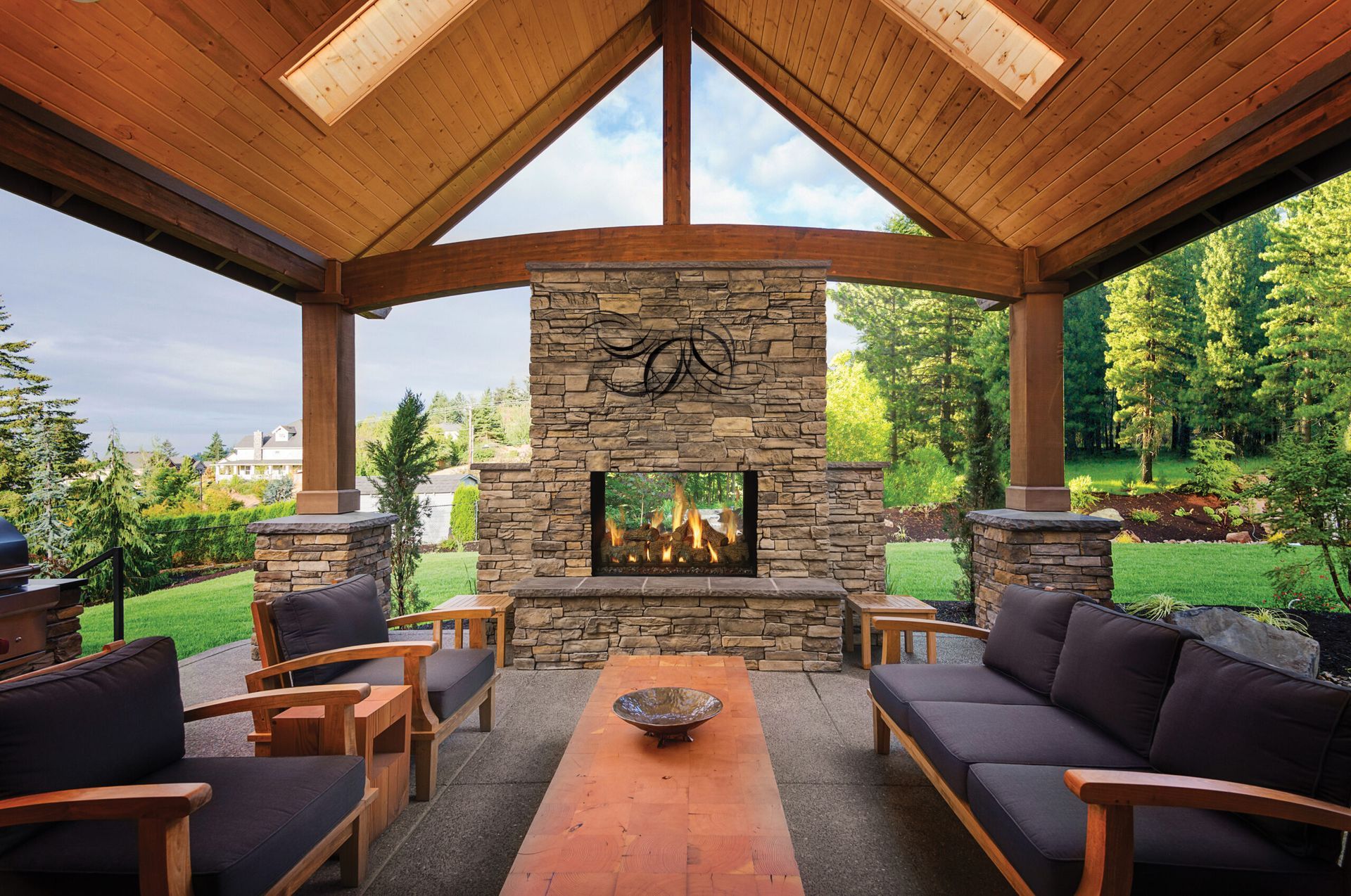 Outdoor patio with stone fireplace, wood beams, and seating.