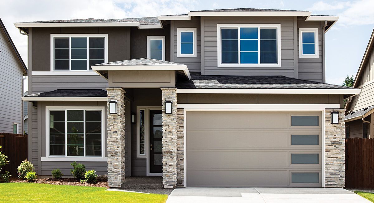 Two-story modern home with gray exterior, stone accents, garage, and large windows on a sunny day. Two-story modern home with gray exterior, stone accents, garage, and large windows on a sunny day.