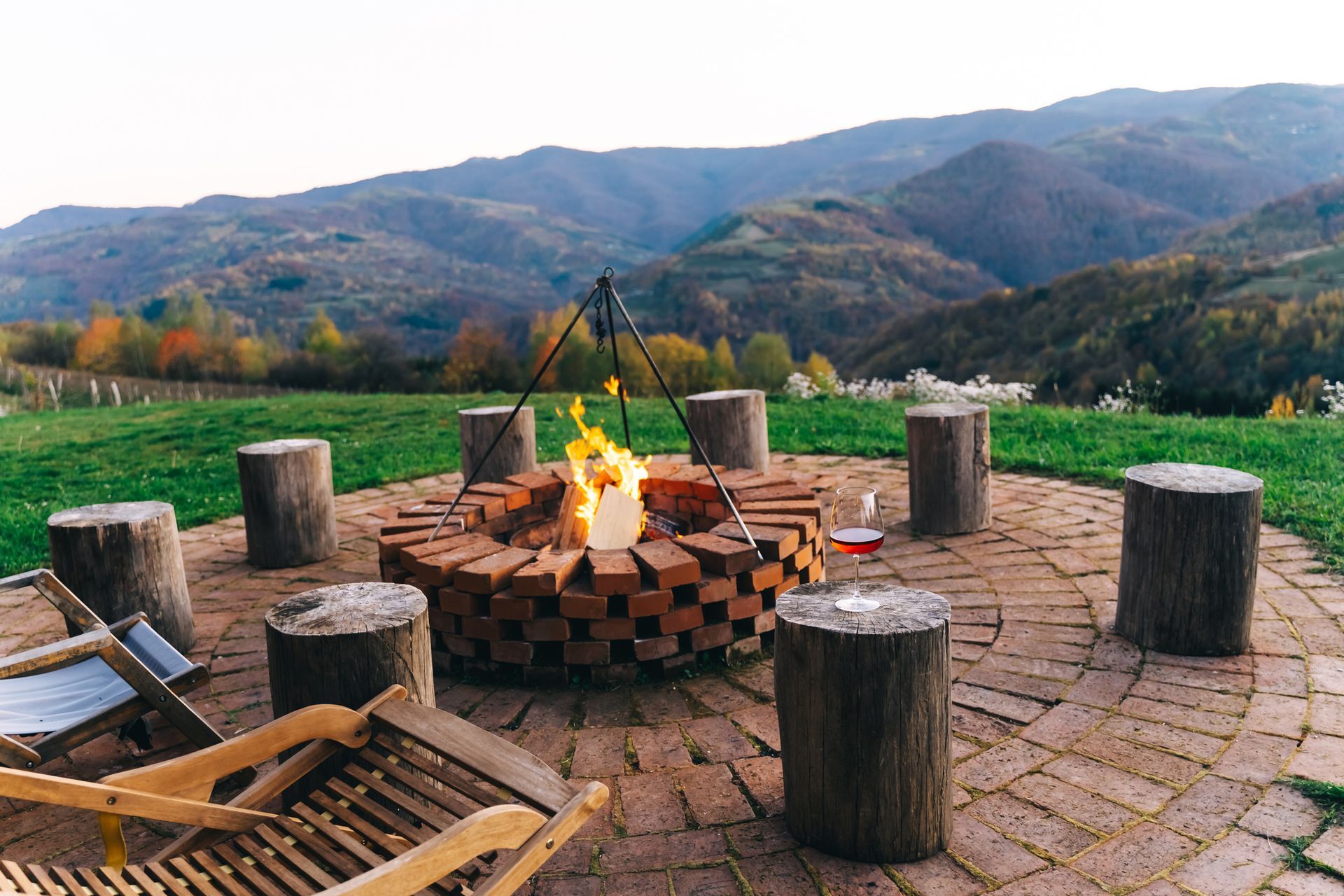 Fire pit with logs seats in front of a mountain landscape.